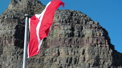 Canadian Flag Waving Against Rocky Mountain
