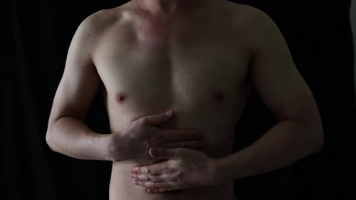 Shirtless Man Holds Stomach in Painful Expression