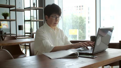 Attractive Mature Businesswoman Working on Laptop in Office or Coworking
