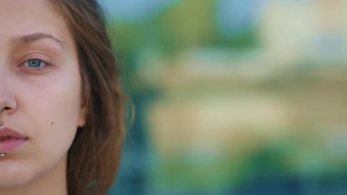 Media cara de la hermosa joven caucásica que mira directamente a la cámara mientras está de pie al aire libre