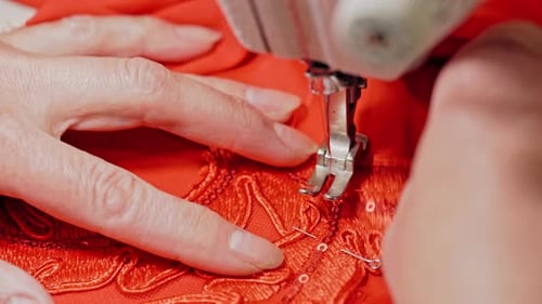 Woman sews clothes on sewing machine. Woman hands drawing pattern on fabric with sewing machine