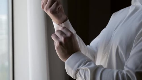 Man Buttons Cuff of White Dress Shirt