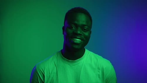 Happy Portrait of Black Man Face Looking at Camera and Smiling in Neon Studio