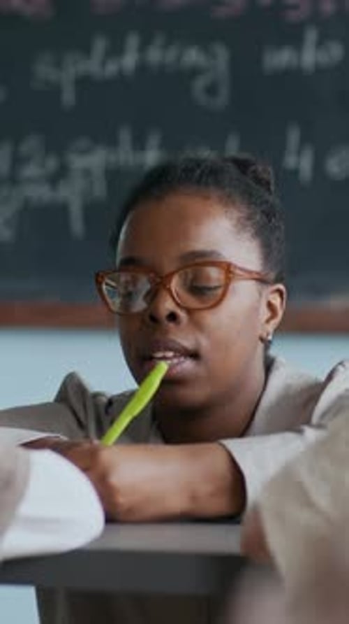 Woman Writing at Desk in Classroom Setting