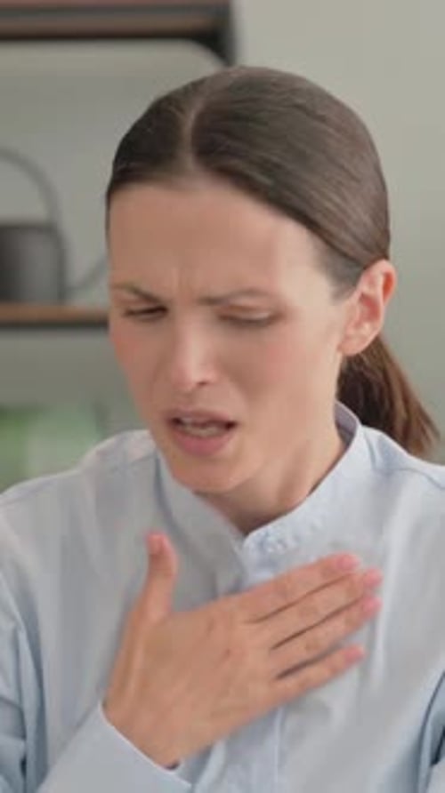 Woman in Light Blue Shirt Coughing Indoors