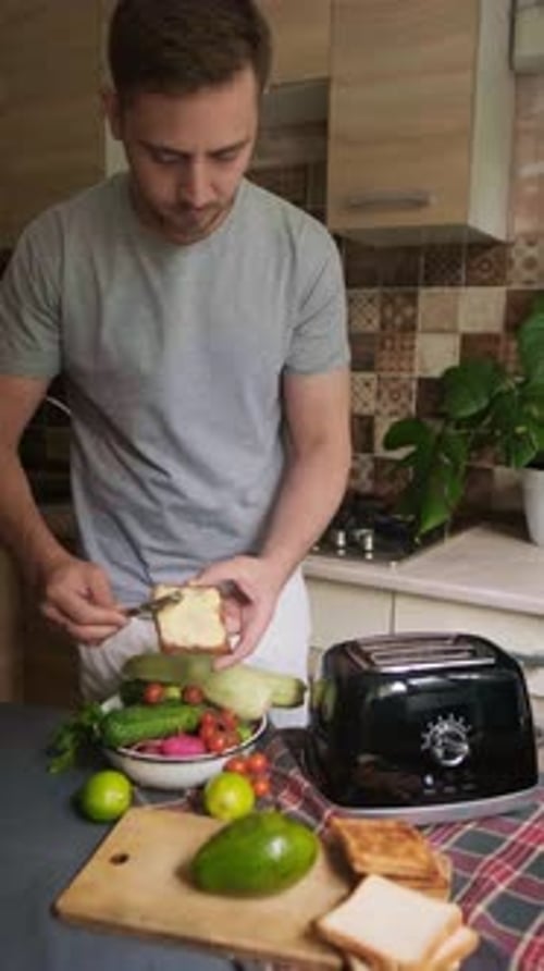 Man Spreads Spread on Bread in Kitchen