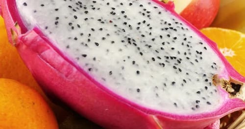 Fruit basket with dragon fruit pitahaya, kiwi, oranges, bananas and apples on a white background.