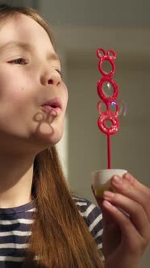 Caucasian Little Girl Child Kid Blowing Soap Bubbles at Home Enjoying Sun Shining Near Window