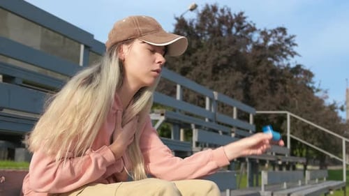 Young Woman Using an Asthma Inhaler on Bench