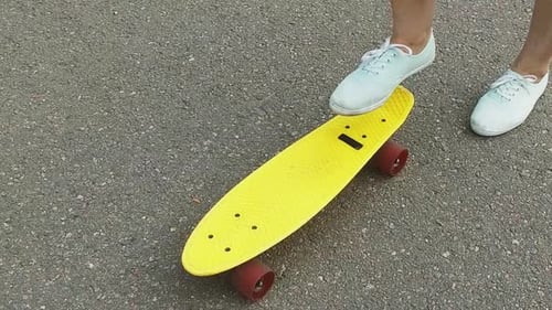 Teenage girl prepares her skateboard for fun on a sunny street