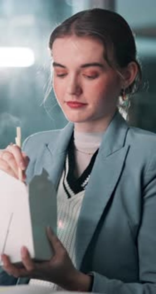 Business woman, night and eating noodles with chopsticks for break or meal time at office desk