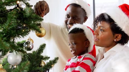 Family Decorates Christmas Tree in Santa Hats