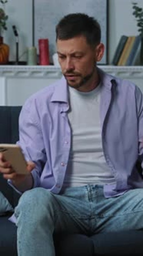 Man Looks at Phone Then Covers Face In Dispair