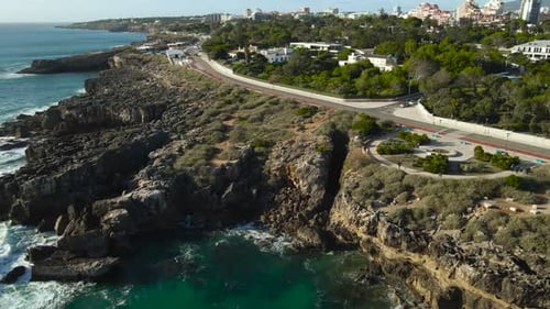 Aerial View of Scenic Coastal Road Winding Along Rugged Cliffs