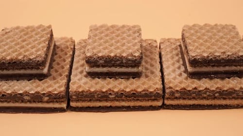 Delicious chocolate waffles with hazelnuts on an orange background.