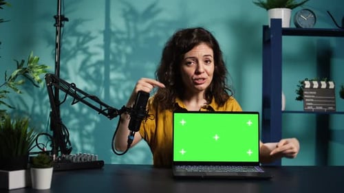 Woman Presenting Laptop with Green Screen in Studio