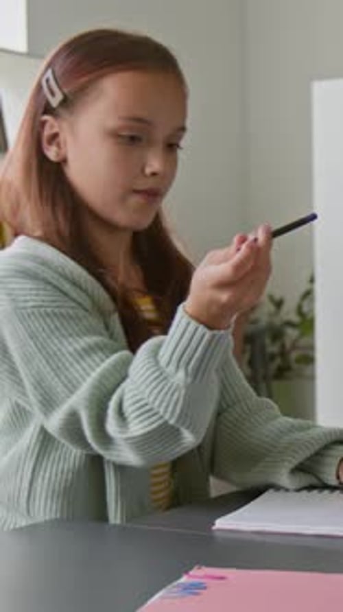 Girl Writes in Notebook While Boy Looks On