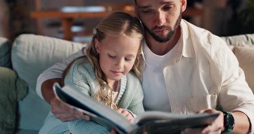 Father and Daughter Reading a Book on Couch