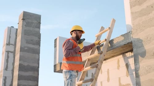 Construction Worker Drilling on Ladder at Job Site