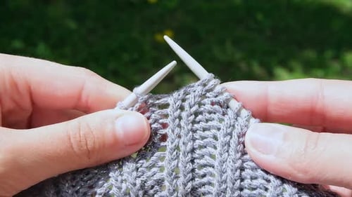 Close Up of a Woman Knits Wool Creating a Warm Gray Handmade Sweater with Her Hands and Sewing