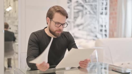 Man Reviews Documents at Home Office Desk