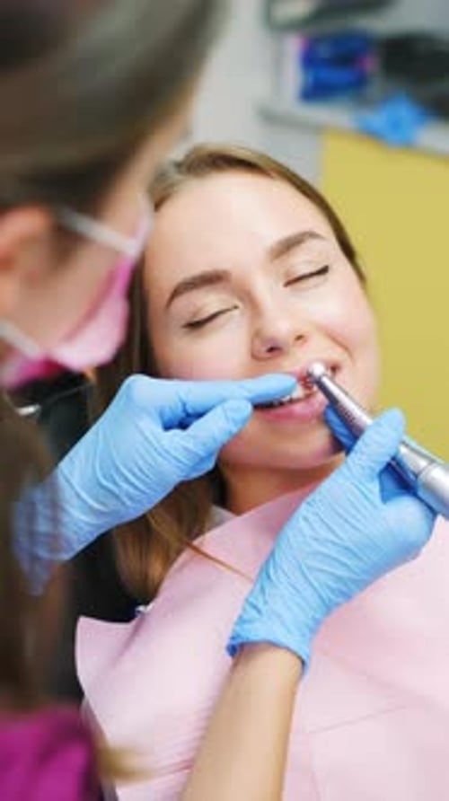 Woman Patient Sitting in Medical Chair During Teeth Grinding Procedure