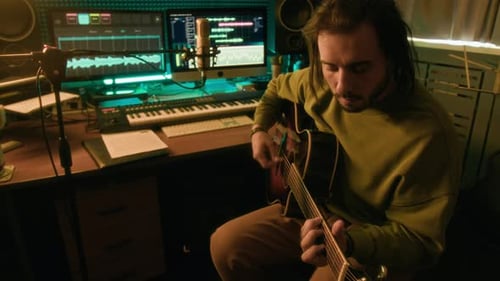 Artist Playing Guitar and Recording Sound on Computer in Studio