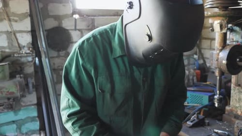Mechanic in Protective Mask Fixing Some Metal Details on Table at Workshop Male Welder in Workwear