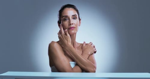 Woman Touches Her Face Against a Light Background