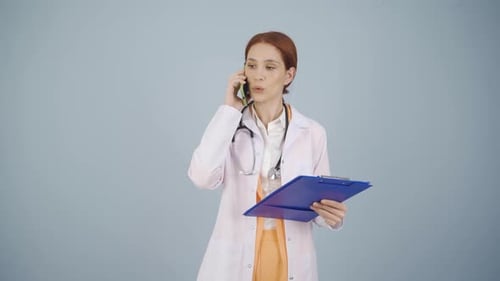 Doctor Talking on Cell Phone Holding Clipboard