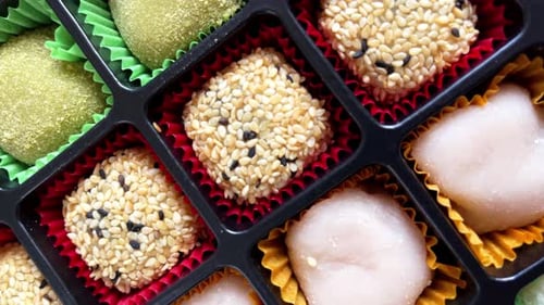 Colorful assortment of mochi desserts arranged in decorative box.