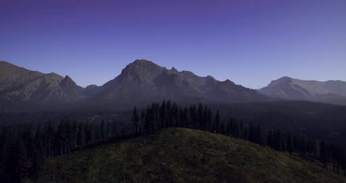 Majestic Mountains Under a Clear Sky at Dusk Near a Forested Area