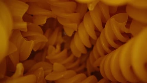 The container with fusilli pasta, the camera flies out of the pasta and they are taken from the tabl