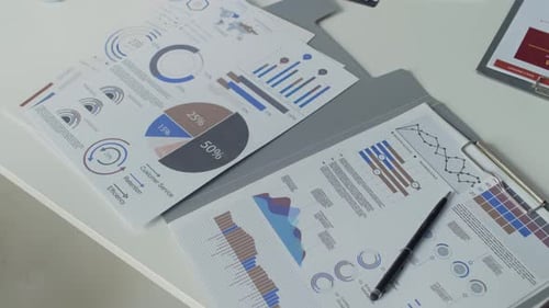 Primer plano de documentos comerciales con tablas y gráficos en el escritorio