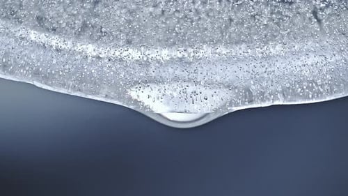 Schmelzender Eisblock mit Wassertropfen, die in Zeitlupe herunterfallen