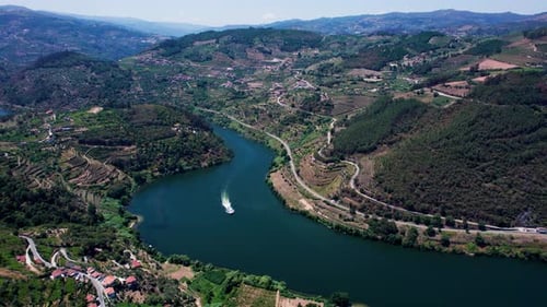 Aerial view of winding river flowing through terraced green mountain hills