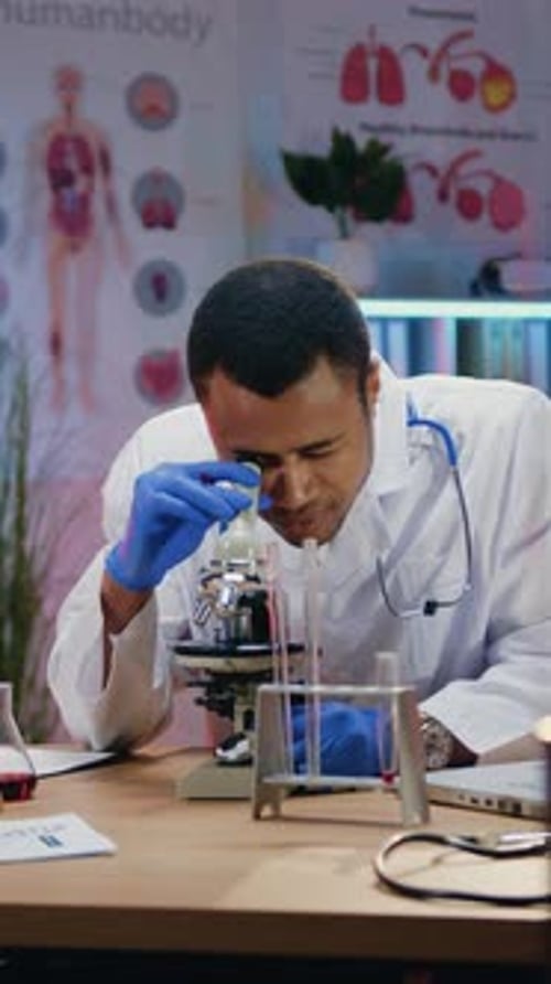 Man in Lab Coat Using Microscope in Lab