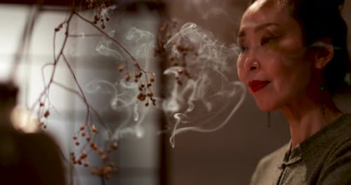 Japanese woman at home contemplating and smelling incense, Kyoto Japan