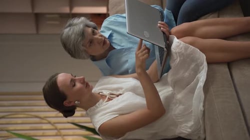 Smiling Women Using Laptop Together on Couch