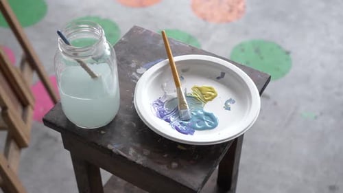 Close up of colorful paints mix together on palette in arts and crafts studio