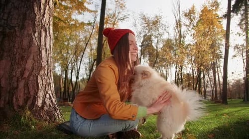 Happy Woman Cuddling Dog in Autumn Park