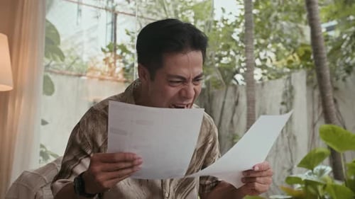 Distressed Man Reacts to Bad News on Paper
