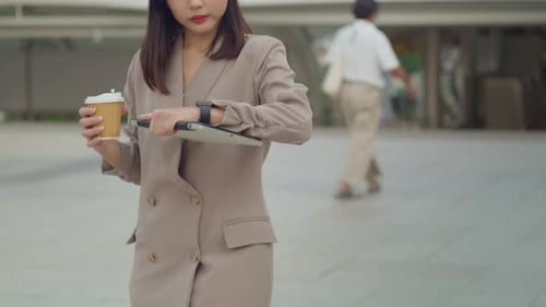 Eine junge, schöne Geschäftsfrau trinkt Kaffee und geht in der modernen Stadt spazieren