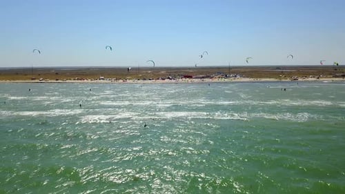 Aerial of Many Kiteboarders with Colorful Kites Flying Over the Blue Sea Lagoon Ride on Kiteboards