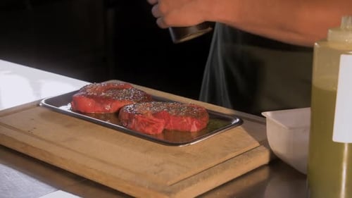 Chef Seasoning Raw Steak with Pepper Mill