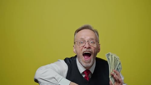 Anciano feliz tirando dinero. Hombre maduro con gafas con pelo gris que sostiene billetes de un dólar