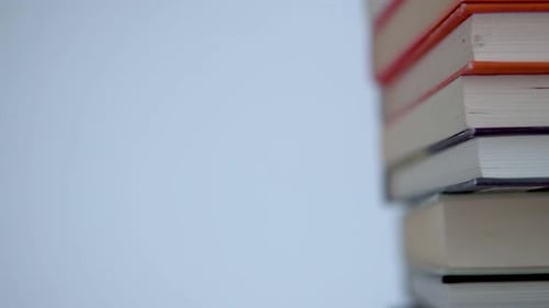 Close-up on a few books lying at the stack. Smooth movement from right to left. Colourful book cover