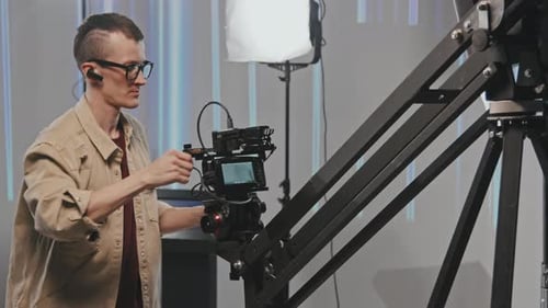 Cameraman Adjusting Camera in Studio