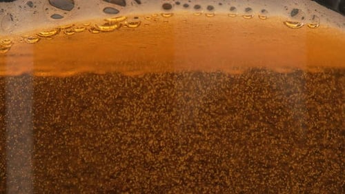 Bolhas em um copo de cerveja em câmera lenta. Uma caneca de cerveja dourada brilha na luz. As bolhas sobem