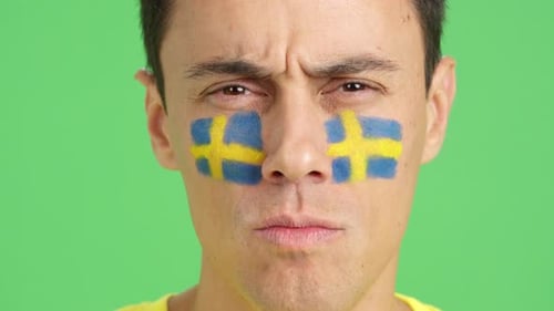 Serious Man with a Swedish Flag Painted on the Face
